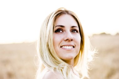 Kırmızı elbiseli, günbatımı buğday sahasının güzel sarışın kadın