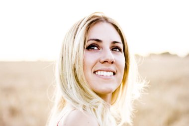 Kırmızı elbiseli, günbatımı buğday sahasının güzel sarışın kadın