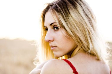 Kırmızı elbiseli, günbatımı buğday sahasının güzel sarışın kadın