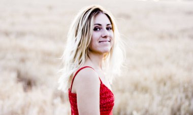 Kırmızı elbiseli, günbatımı buğday sahasının güzel sarışın kadın