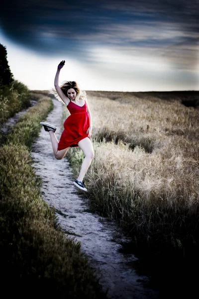 Belle femme blonde en robe rouge sur un chemin dans le champ de blé — Photo