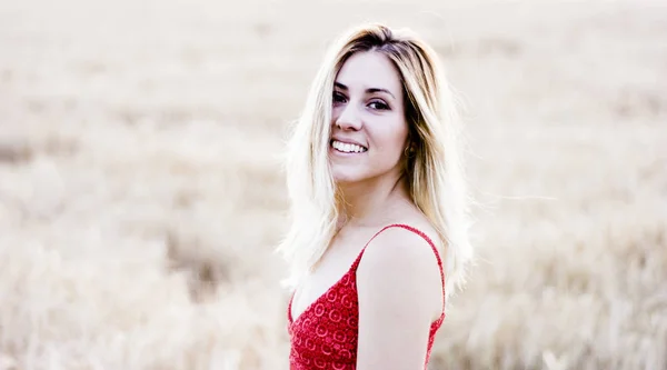 해질녘 밀 필드에 빨간 드레스에 아름 다운 금발 여자 — 스톡 사진