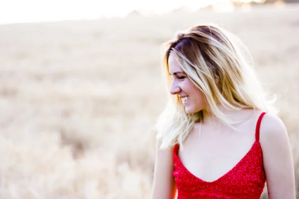 Bella donna bionda in abito rosso, su un campo di grano al tramonto — Foto Stock