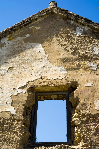 Casa en ruinas ventana a través de la cual se puede ver el cielo azul — Foto de Stock