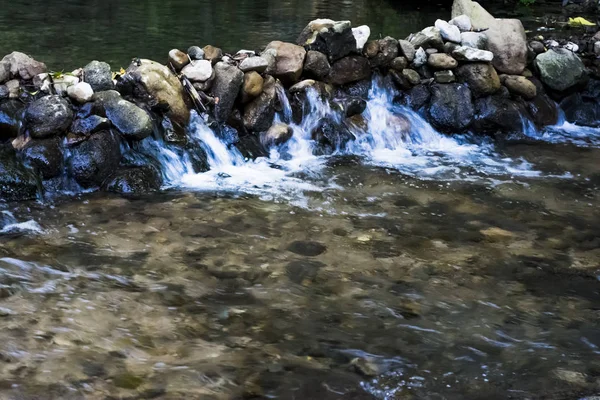 Krajina z říční vody tekoucí hedvábný, skály a stromy — Stock fotografie