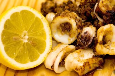 Fried squids ve shipirons ahşap plaka üzerinde limonlu