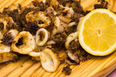 Fried squids ve shipirons ahşap plaka üzerinde limonlu
