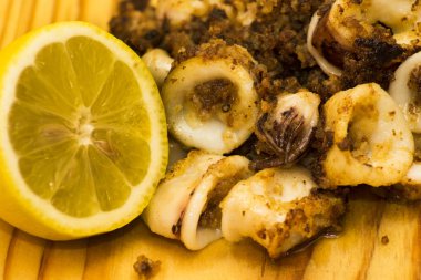 Fried squids ve shipirons ahşap plaka üzerinde limonlu
