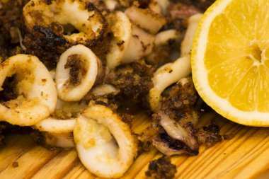 Fried squids ve shipirons ahşap plaka üzerinde limonlu