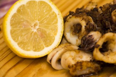 Fried squids ve shipirons ahşap plaka üzerinde limonlu