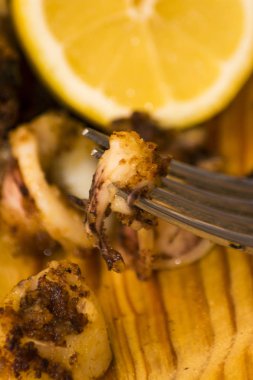 Fried squids ve shipirons ahşap plaka üzerinde limonlu