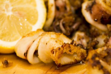Fried squids ve shipirons ahşap plaka üzerinde limonlu