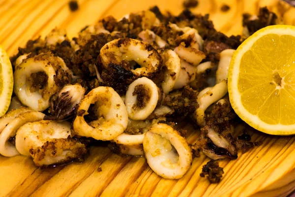 Calamari fritti e shipiron con limone su un piatto di legno — Foto Stock