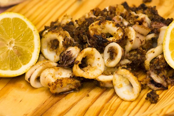Fried squids ve shipirons ahşap plaka üzerinde limonlu