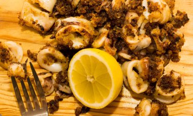 Fried squids ve shipirons ahşap plaka üzerinde limonlu
