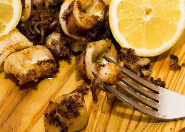 Fried squids ve shipirons ahşap plaka üzerinde limonlu