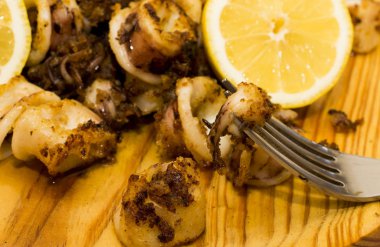 Fried squids ve shipirons ahşap plaka üzerinde limonlu