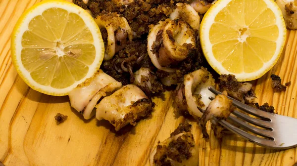 Fried squids ve shipirons ahşap plaka üzerinde limonlu