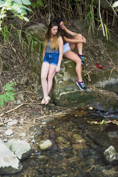 Dos hermosas mujeres en la naturaleza en la orilla de un río de montaña — Foto de Stock