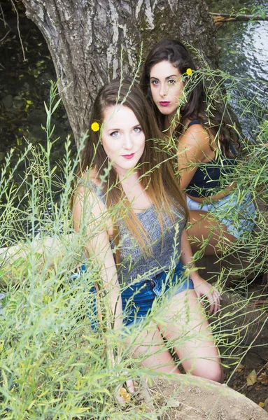 Dos hermosas mujeres en la naturaleza en la orilla de un río de montaña — Foto de Stock