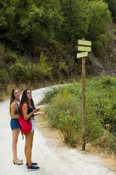 Dos hermosas mujeres en un poste con señales de tráfico en blanco en la naturaleza en — Foto de Stock