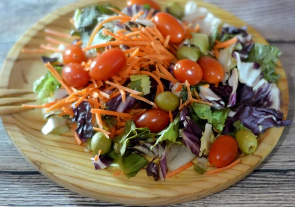 Свежий салат на деревянной тарелке — стоковое фото