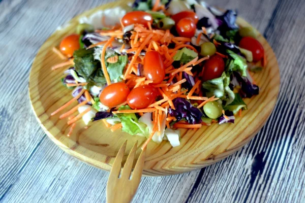 Fresh salad on a wooden plate — Stock Photo, Image