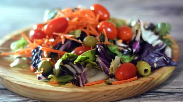 Insalata fresca su un piatto di legno — Foto Stock