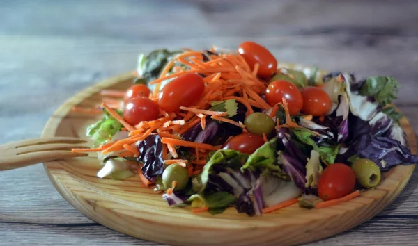 Fresh salad on a wooden plate — Stock Photo, Image