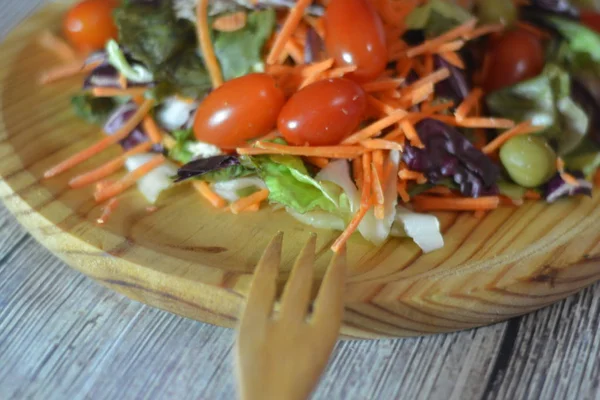Frischer Salat auf einem Holzteller — Stockfoto
