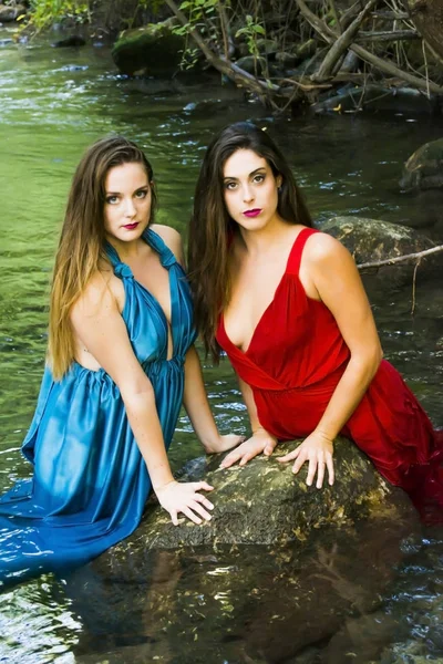 Duas mulheres bonitas na margem de um rio de montanha com noite — Fotografia de Stock