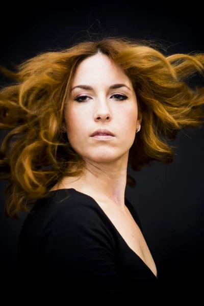 Portrait d'une belle femme secouant ses cheveux sur fond noir — Photo
