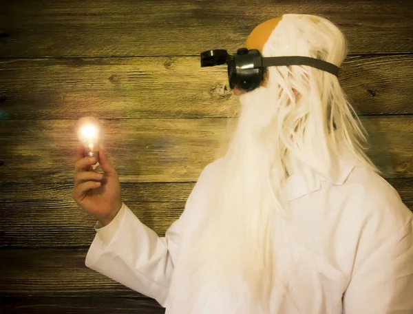 Crazy scientist elderly man holding an inexplicably lit bulb wit — Stock Photo, Image