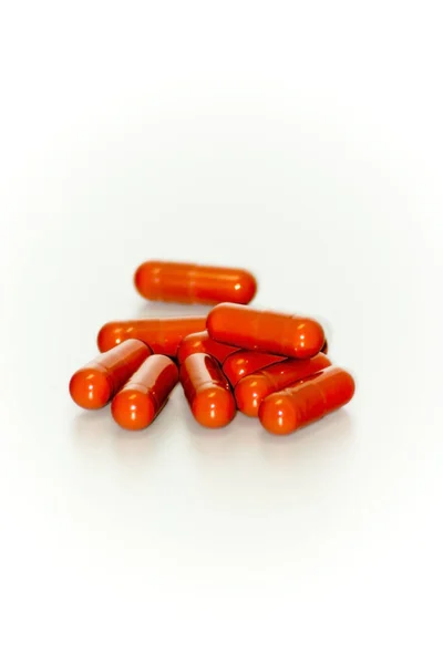 Beaucoup de pilules rouges sur fond blanc — Photo