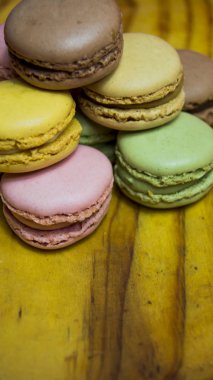 Ahşap tabakta izole edilmiş renkli makaronlar, tipik Fransız yemekleri.