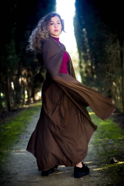 Beautiful woman with cape on a path in the woods