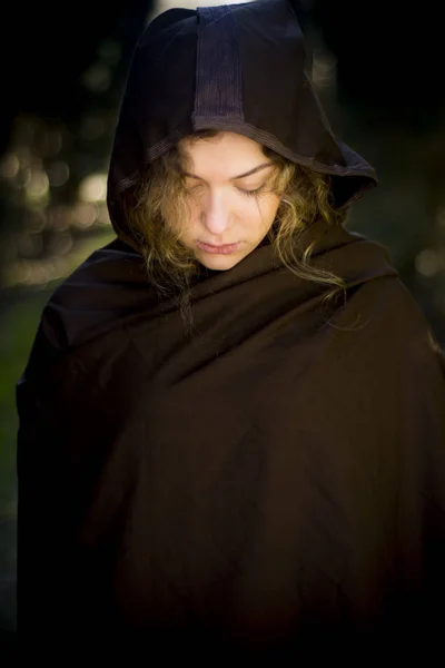 Beautiful woman with cape on a path in the woods