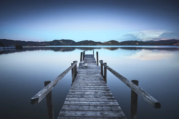 Деревянный пирс или причал на голубом озере закат и отражение неба на — стоковое фото