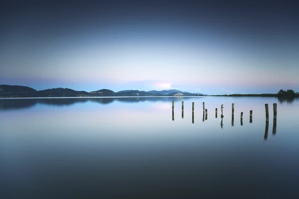 Деревянный пирс или причал остается на голубом озере закат и небо refle — стоковое фото