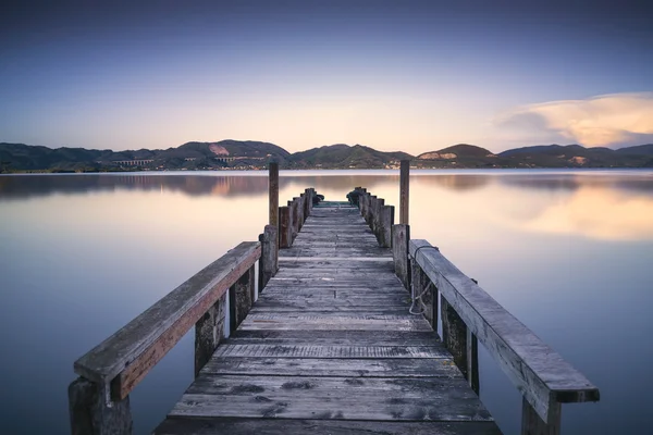 Muelle de madera o embarcadero en un atardecer lago azul y reflejo del cielo en —  Fotos de Stock