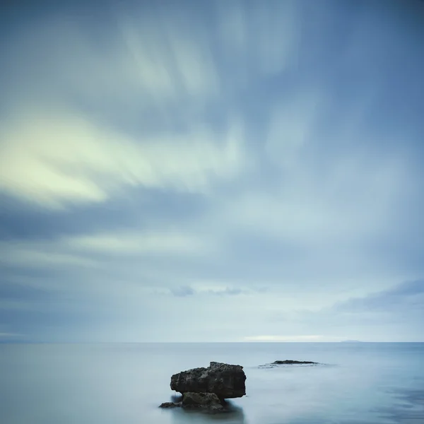 Kötü hava bulutlu gökyüzü altında mavi okyanusun karanlık kayalar. — Stok fotoğraf