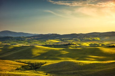 Tuscany Bahar, günbatımı üzerinde inişli çıkışlı tepeler ve yeşil alanlar. Kırsal 