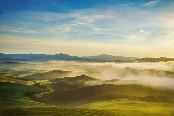 Volterra nebbioso panorama, dolci colline e campi verdi al sole — Foto Stock