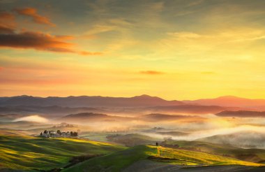 Volterra sisli panorama sunse üzerinde inişli çıkışlı tepeler ve yeşil alanları,