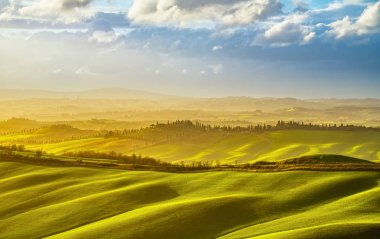 Gün batımında inişli çıkışlı tepeler, tarla, çayır, Tuscany puslu panorama.