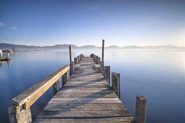 Wooden pier or jetty and lake at sunrise. Torre del lago Puccini