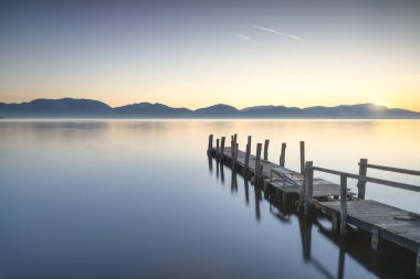 Ahşap iskele ya da iskele ve göl, gün doğumunda. Torre del lago Puccini