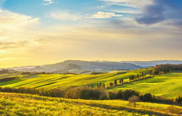Volterra panorama, κυλιόμενοι λόφοι, πράσινα λιβάδια και λευκός δρόμος. Τ — Φωτογραφία Αρχείου