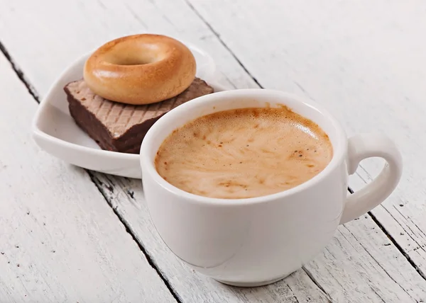 Cup of coffee and delicious baked cookies on old wooden background. — Stock Photo, Image