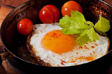 Bir tavada kızarmış yumurta ile acı biber serpilir.